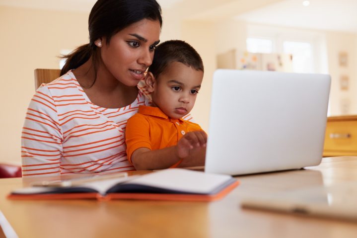 Mother And Son In Kitchen Looking At Laptop Together
